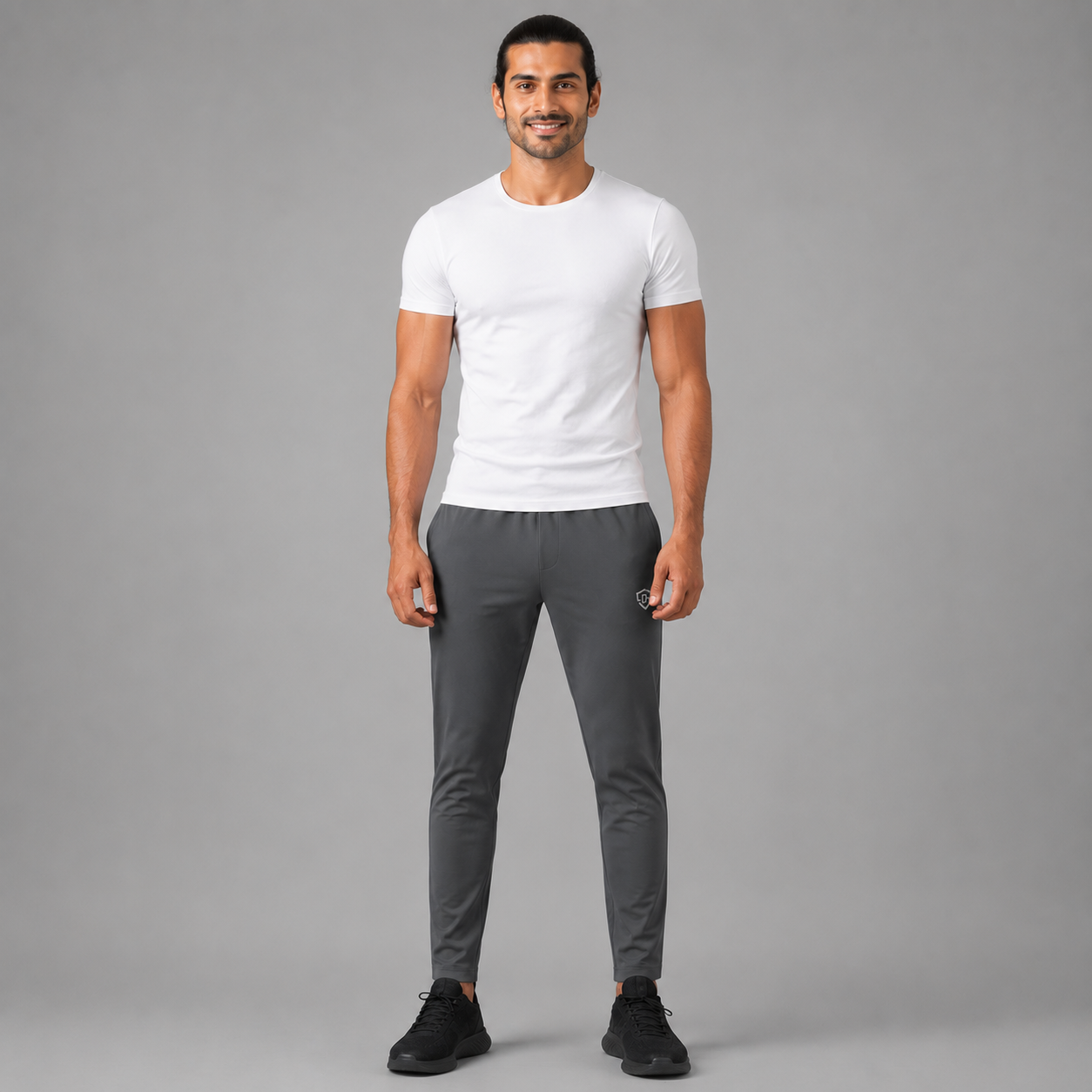 A man modeling a Charcoal gray trousers against a solid gray studio background.